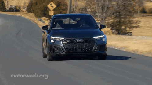 a black car is driving down a road with a motorweek.org logo in the corner
