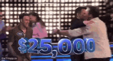 a group of people are hugging each other in front of a sign that says $ 25,000 .