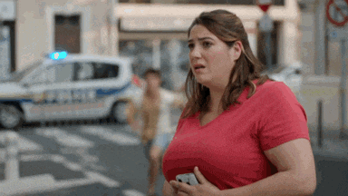 a woman in a red t-shirt is standing in front of a police car