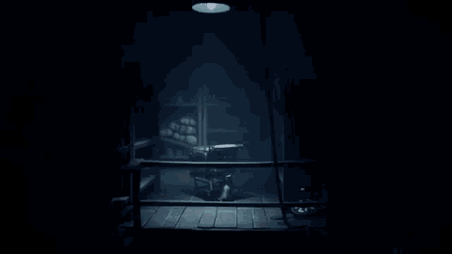 a person is standing in a dark room looking out of a window at something .