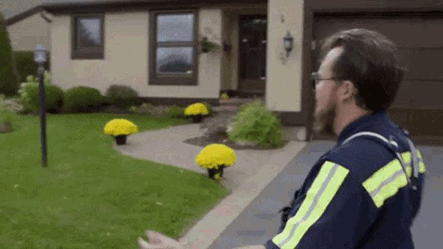 a man standing in front of a house with yellow flowers in pots