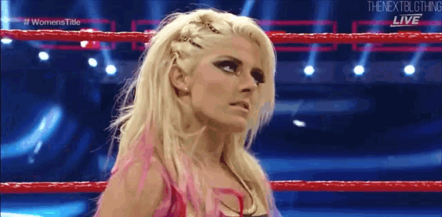 a female wrestler is standing in a boxing ring .