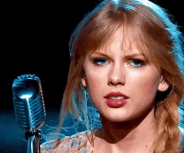 a close up of a woman 's face with a microphone in the background