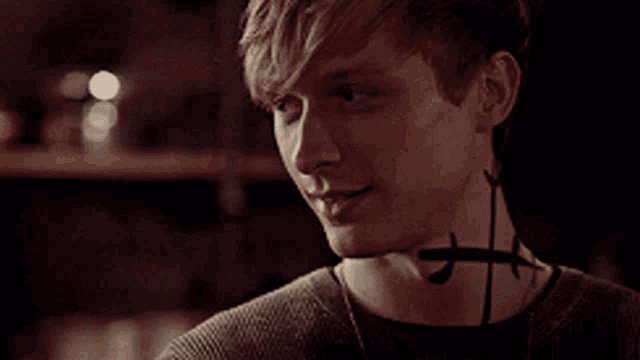 a young man with a tattoo on his neck is smiling