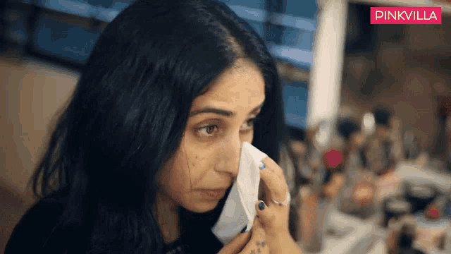 a woman wipes her face with a napkin in front of a pinkvilla banner