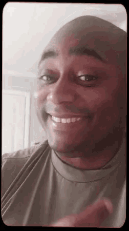 a man in a green shirt is smiling and pointing