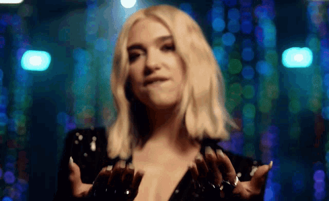 a woman in a black sequined dress is dancing in a dark room