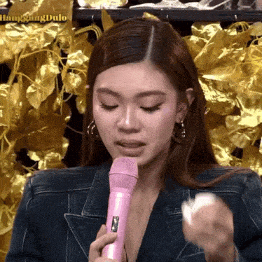 a woman is holding a pink microphone in her hand .