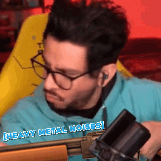 a man wearing glasses holds a gun in front of a microphone with the caption heavy metal noises