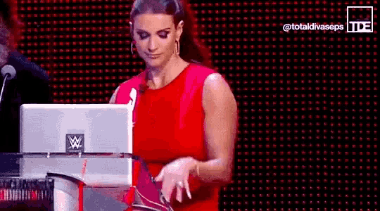 a woman in a red dress is standing in front of a laptop on a podium .