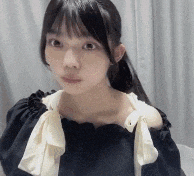 a close up of a woman wearing a black off the shoulder top with a white bow .