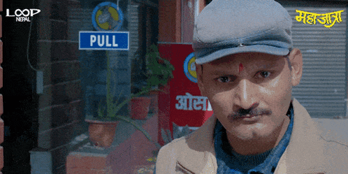 a man wearing a hat is standing in front of a sign that says pull