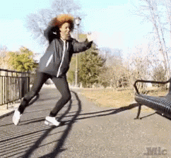 a woman is jumping in the air in front of a bench that says mic on it