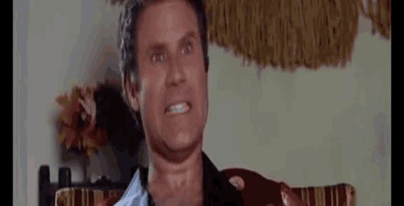 a man is making a funny face while sitting in a chair in a living room .