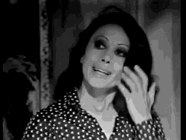 a black and white photo of a woman in a polka dot shirt smiling .