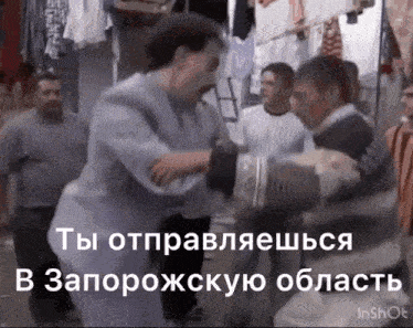 a group of men are standing in a room and one of them is holding another man in his arms .