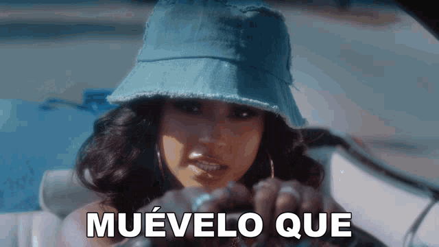 a woman wearing a denim hat is sitting in a car with the words muvelo que written on the screen