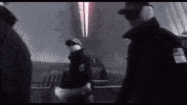 a group of people are standing in a dark room .