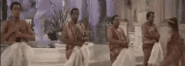 a group of people are dancing in a room with a statue in the background