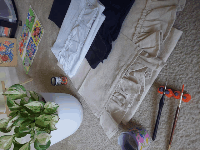 a painting brush sits on a table next to a plant and some clothes