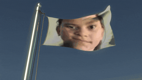 a flag with a girl 's face on it against a blue sky