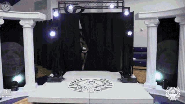 a woman stands on a stage with a laurel wreath on the floor and a sign that says grand prix