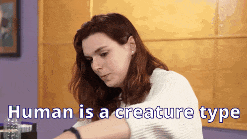 a woman is sitting at a table with the words human is a creature type written on the bottom