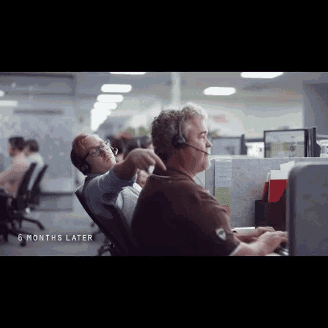 a man and a woman are sitting at a desk in an office .