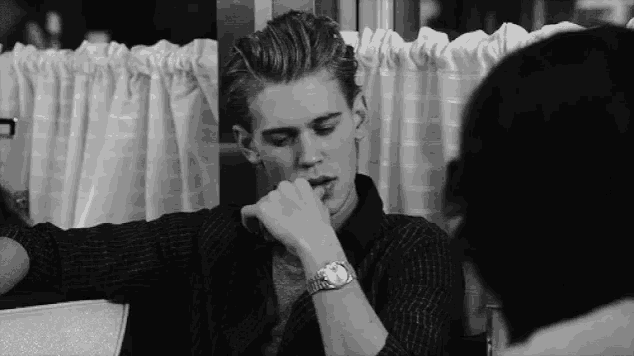 a man wearing a watch is sitting at a table with a woman in a diner .