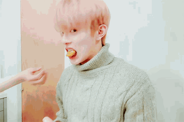 a young man with pink hair is eating a chicken nugget with his tongue out