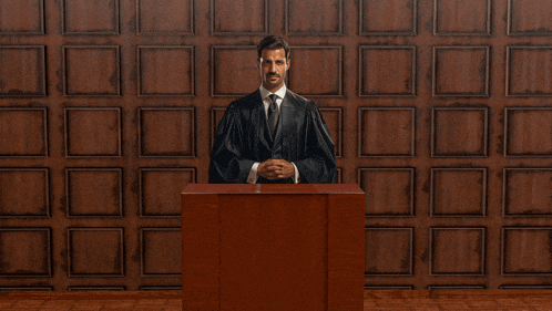 a man in a judge 's robe stands behind a podium