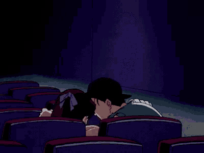 a man and a woman are sitting in a theater with their arms outstretched .