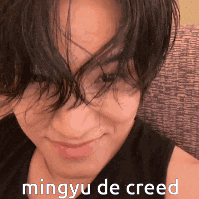 a close up of a person 's face with the words mingyu de creed written below it