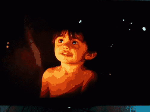 a little boy without a shirt is looking up at the sky
