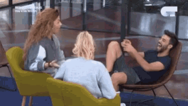 a man is sitting in a chair with his legs crossed and two women are sitting next to him .
