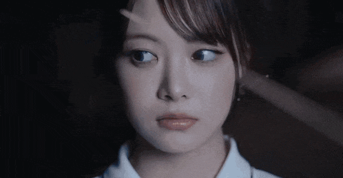 a close up of a woman 's face in a dark room with a blurred background .