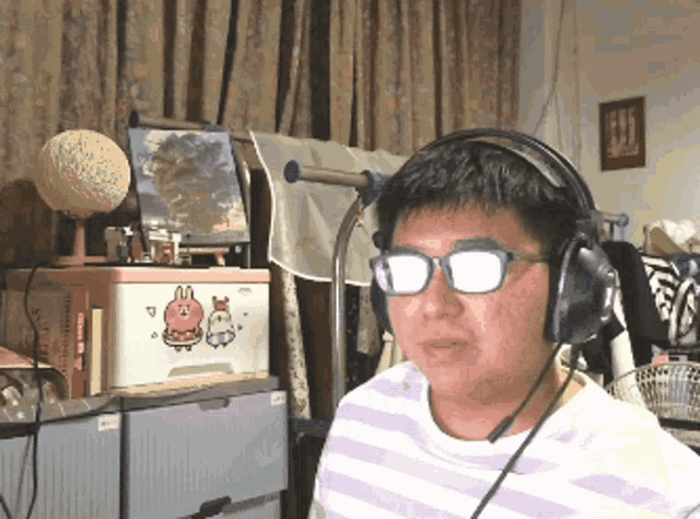 a man wearing glasses and headphones is sitting in front of a pink box with a bunny on it