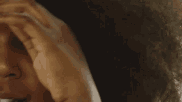 a close up of a woman 's face with her hand on her head .