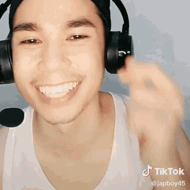 a man wearing headphones and a white tank top has a tiktok sticker on his chest