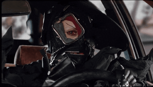 a person wearing a gas mask and goggles sitting in a car