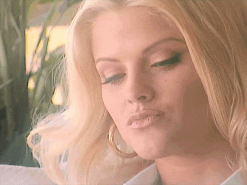 a close up of a woman 's face with blonde hair and hoop earrings