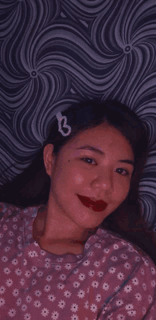 a girl wearing a pink shirt with white flowers and a heart hair clip