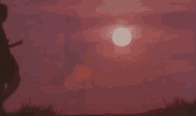 a silhouette of a person standing in front of a sunset