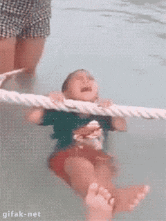 a baby is crying in a swimming pool with a rope around his neck