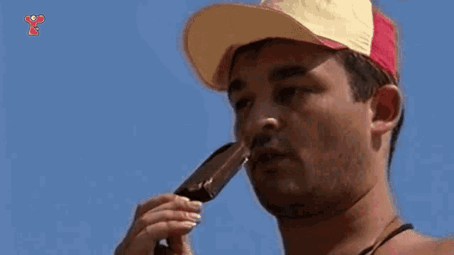 a man wearing a hat is eating a chocolate bar
