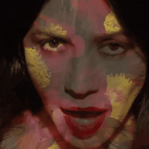 a close up of a woman 's face with a yellow flower on her forehead