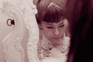a woman is looking at herself in a mirror while wearing a necklace .