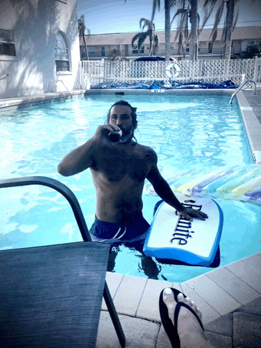 a man in a swimming pool with a board that says " dynamite " on it