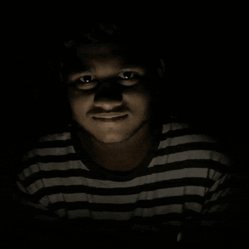 a man in a black and white striped shirt looks at the camera