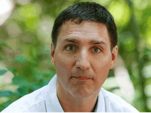a man wearing a white shirt is looking at the camera